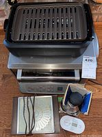 Photo showing George Foreman grill on top of Cuisinart stainless steel toaster oven with rotary food chopper in box and warming tray