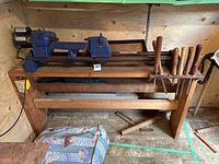 Side view of Drillmaster wood lathe with motor mounted on wooden stand, along with woodturning chisels in holder attached to the stand.