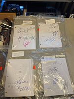 Four autographed scripts in plastic bags with visible signatures and typed titles.