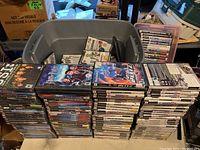 Large box of over 190 PS2 games stacked in piles, showcasing case spines and covers with artwork and titles visible.
