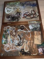 Top view of the wooden display box filled with assorted necklaces, bracelets, and earrings showing variety of bead colors and styles.