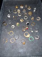 Top-down view of 31 assorted custom rings showing variety of designs, stones, and finishes