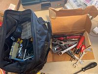 View of soft carrying bag filled with assorted hand tools including screwdrivers, wrenches, pliers, sockets, and a small parts organizer.