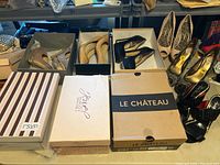 Overall view of 9 pairs of women's high heel shoes in assorted boxes and displayed outside boxes showing various styles and colors.