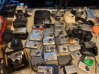 Overhead view of over 20 assorted digital and film cameras and accessories