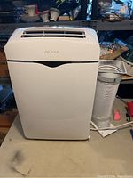 Front view of white Noma portable air conditioner with vent slots at the top and Noma branding on front.
