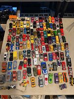 Full lot of vintage Hot Wheels cars and trucks arranged in rows showing variety and condition.