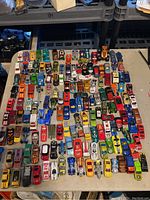 Overview of the full lot showing approximately 85 vintage Hot Wheels cars, many with unique paint designs and in various colors.