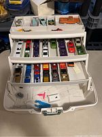 Full view of open white carrying case with multiple trays filled with Hot Wheels cars
