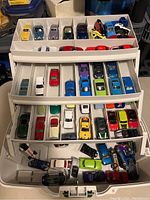 Top view of the closed white carrying case with three trays full of vintage Hot Wheels cars in multiple colors and models.