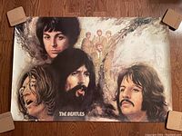 Large Beatles poster featuring stylized portraits of band members, measures visible on wooden floor, centered composition.