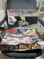 Photo showing two vintage Star Wars model kits, the Return of the Jedi Shuttle Tydirium and the Empire Strikes Back Rebel Base kits with heavily worn boxes.