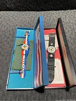 Two vintage Mickey Mouse watches in their original boxes shown side by side on black textured surface.