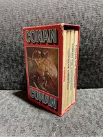 Side view of four Conan softcover books in red slipcase showing cover artwork and title Conan Conan.