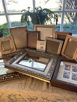 Photo of 12 assorted picture frames including large ornate gold and silver frames, two dark brown frames for art pieces, and a few smaller frames with stands.