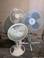 Three floor fans grouped together; white Galaxy fans and blue Westinghouse fan