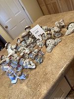 Wide shot of over 25 Dreamsicles angel figurines arranged on a table displaying lambs, angels with floral crowns, and various poses.