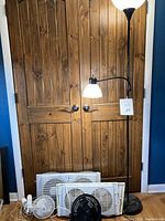 Full image showing four fans of different sizes and a metal floor lamp with white top and side reading light against a wooden door background.