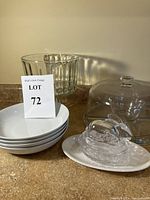Photo showing a glass compote, four white bowls, a bunny butter dish on a plate, large clear bowl, and clear glass cake plate with cloche.