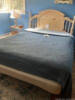Full view of assembled bed with mattress, bedding, wooden headboard and footboard with remotes on mattress
