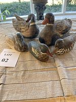 All five ceramic duck figurines grouped on a cloth surface showing scale and finish
