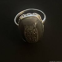 Top view of ring showing large rectangular smokey stone set in sterling silver with filigree detailing around the base of the stone.