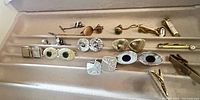 Front view of assorted vintage mid-century modern cufflinks and tie bars arranged in a jewelry box slot.