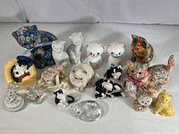 Full view of the lot showing multiple cat figurines in various colors, materials, and sizes including floral and ceramic types.