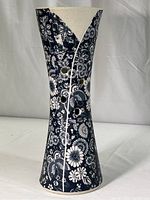 Full view of vase showing its tall, tapered form with dark blue chrysanthemum floral pattern and four circular cut holes.