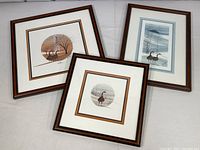 Three framed goose prints arranged lying on a surface, showing the artwork and frames in overview.