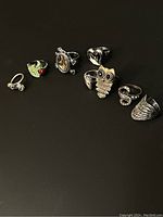 Photo showing all 8 silver tone rings with distinct designs on black background.