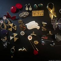 Top view showing diverse assortment of vintage clip-on earrings, pins, brooches, and decorative jewelry pieces on dark background.