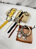 Photo showing seven vintage watches displayed on cushion and brown cloth, highlighting variety in strap colors and watch face designs.