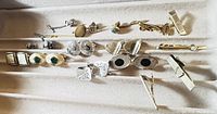 Photo of assorted vintage cufflinks and tie clips arranged in a box.