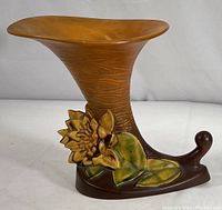 Side view of the Roseville cornucopia vase with floral detail and textured brown surface.