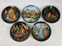 Overview of the five Russian collector plates arranged on a white surface showing varied colorful scenes and themes.
