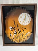 Full view of rectangular vintage wood framed wall clock with glass featuring painted wheat silhouettes against brown and orange gradient background.