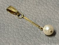 Close-up image of the 14K gold pearl drop pendant showing the pearl at the end of a gold bar and the gold bail.