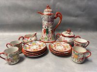 Full set including coffee pot, creamer, sugar bowl, dessert plates, demitasse cups and saucers shown on a grey backdrop