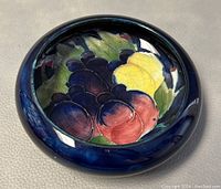 Top view showing bowl's colorful fruit design, glossy dark blue border, and round shape.
