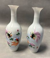 Pair of white porcelain vases with bas-relief koi fish and floral designs, approximately 5.5 inches tall.