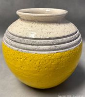 Side view of vintage ceramic vase showing yellow textured glaze on lower half and off-white textured glaze with horizontal ring details on upper half