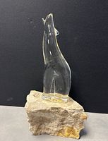 Front view of clear glass Inuit-style sculpture on limestone base showing detailed animal figure in howling position.