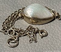 Close-up of the large teardrop-shaped freshwater pearl set in silver bezel with part of chain and clasp visible.