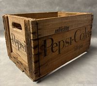 View of crate showing Pepsi-Cola branding on side with cut-out handle and reinforced corners.