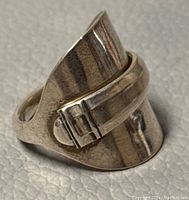 Close-up showing the sterling silver ring with buckle design and curved shape.