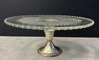 Side view of cake stand showing crystal plate with Candlewick bead edge and sterling silver weighted pedestal base with beaded trim.