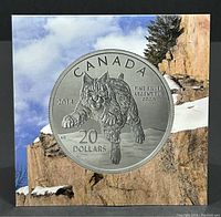 Front view of the packaged coin showing the bobcat image on the coin with natural rocky background artwork on the packaging.