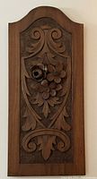 Full view of the wood carved panel showing the entire floral design and scroll motifs within a shield-shaped inset area and an arched top frame