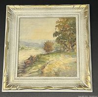Framed watercolour painting showing the full artwork and frame, depicting trees and riverbank scene with signature visible in bottom right.